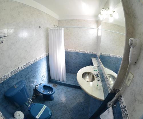 uma casa de banho com um lavatório, um WC e um espelho. em Hotel Mayoral em Rosário