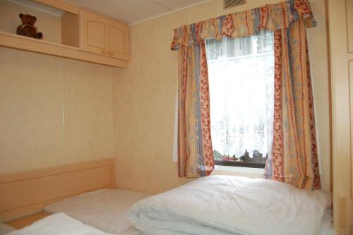 a bedroom with a bed and a window at Caravan B26 at The Woodlands in Tywyn