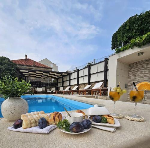 una bandeja de comida en una mesa junto a una piscina en Apartments Miljas, en Dubrovnik