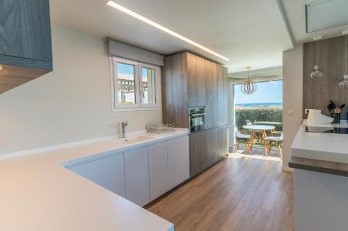 a kitchen with white cabinets and a dining room with a table at Exquisita Villa Frente al Mar in Sagunto