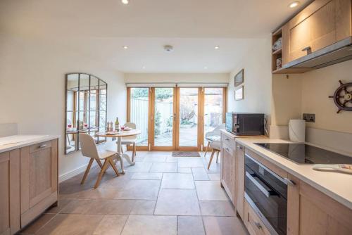 eine Küche mit Theke und Tisch mit Stühlen in der Unterkunft Pebbles Cottage, Southwold in Southwold