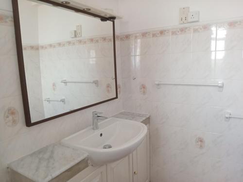 a white bathroom with a sink and a mirror at Rockwood Apartment Colombo 7 in Colombo