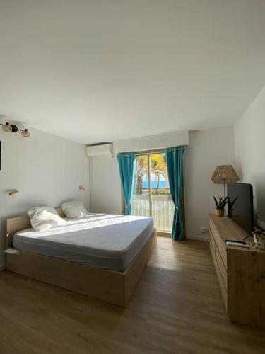 une chambre avec un grand lit et une fenêtre dans l'établissement Grands studio en bord de mer, à Cagnes-sur-Mer