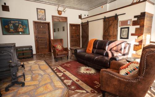 a living room with a leather couch and a fireplace at The Frenchman Suites in Silverton