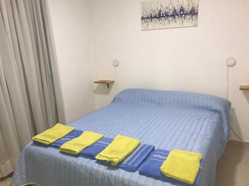 Un dormitorio con una cama azul con toallas amarillas. en Departamento Libertad en Puerto Madryn