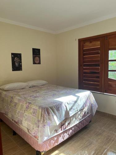 a bedroom with a bed with a quilt on it at Chalé Guaramiranga-CE in Guaramiranga