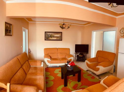 Empire Apartments في برميت: غرفة معيشة مع أثاث برتقالي وتلفزيون