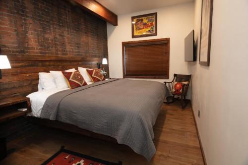 a bedroom with a bed and a brick wall at The Frenchman Suites in Silverton