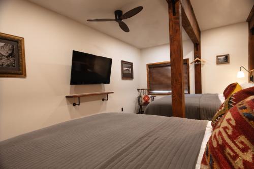 a bedroom with a bed and a flat screen tv at The Frenchman Suites in Silverton