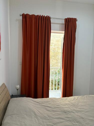 a bedroom with an orange curtain and a window at Traditional Maltese Sea View Apartment in Kalkara