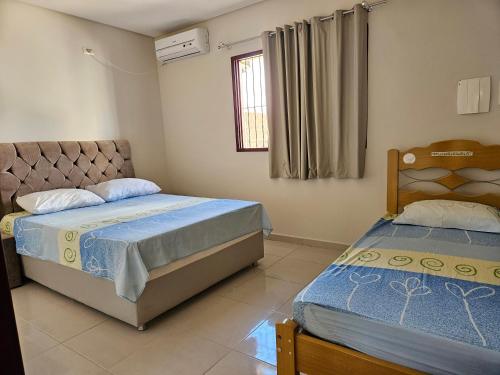 um quarto com 2 camas e uma janela em Casa em Tamandaré em Tamandaré