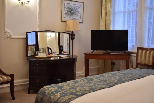 a bedroom with a bed and a desk with a television at Botleigh Grange Hotel & Spa in Southampton