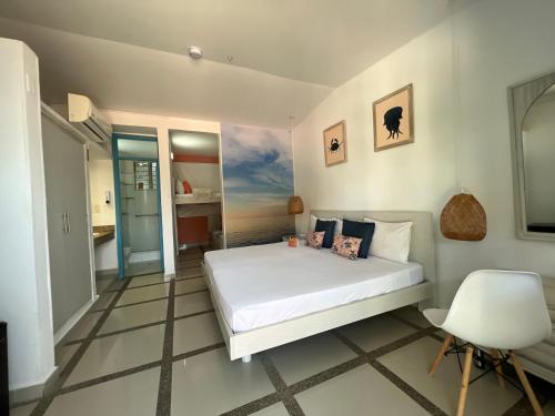 sypialnia z białym łóżkiem i krzesłem w obiekcie GIO Hotel Tama Santa Marta w mieście Santa Marta
