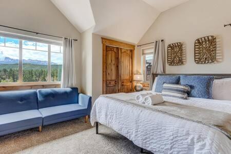 une chambre avec un grand lit et un canapé bleu dans l'établissement Cabin~Views~Heart of Town~W&D~Fireplace~Kitchen, à Woodland Park