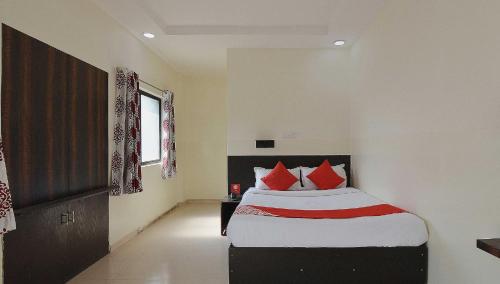um quarto com uma cama com almofadas vermelhas em Collection O Krushna Rooms em Vagholi