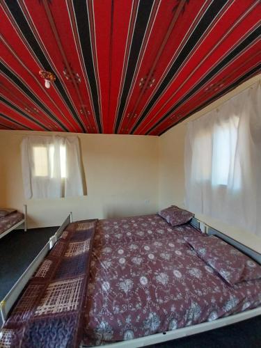 um quarto com uma cama e um tecto vermelho em Wadi Ghwere Camp مخيم وادي الغوير em Al Khuraybah