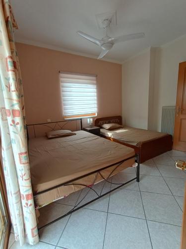 two beds in a room with a window at ENJOY APARTMENT in Ovriá