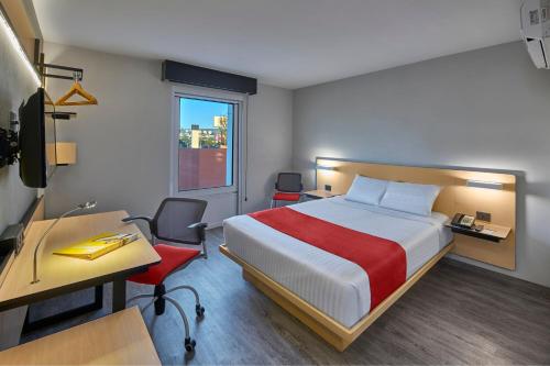 a hotel room with a bed and a desk and a desk at City Express by Marriott Queretaro in Querétaro
