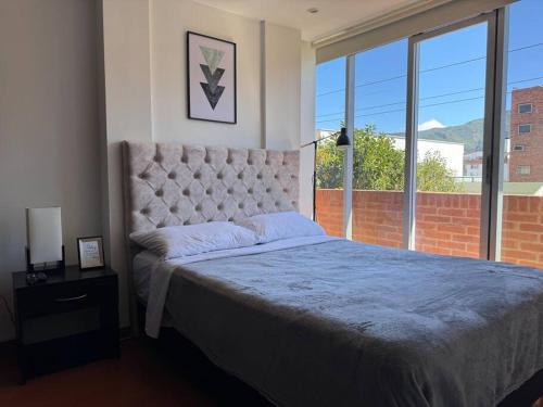a bedroom with a large bed and a large window at Acogedor apartamento cerca a Unicentro in Bogotá