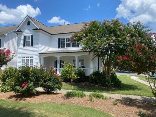 a white house with a tree and flowering bushes at Davidson House - 3 beds 2.5 baths in Davidson