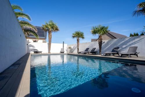 a swimming pool with chairs and palm trees at Omaha gîtes in Vierville-sur-Mer