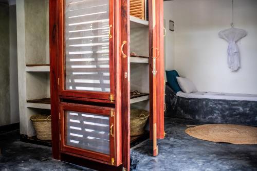 a wooden shelf with glass doors in a room at Baobab Bungalows in Jambiani
