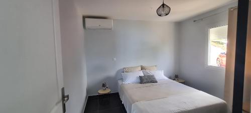 - une chambre avec un lit blanc et une fenêtre dans l'établissement Les Gîtes Kajou, à Bouillante