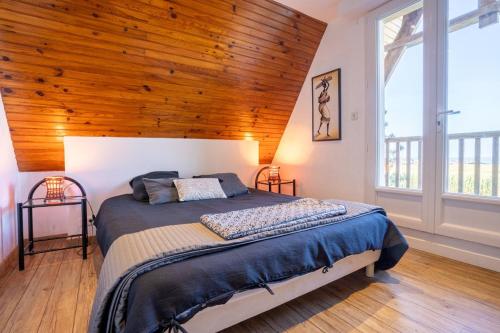 Un dormitorio con una cama grande con techo de madera. en Omaha gîtes, en Vierville-sur-Mer