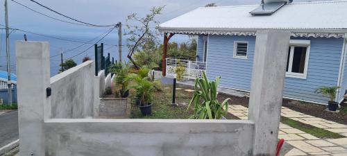 a fence in front of a blue house with plants at Les Gîtes Kajou in Bouillante