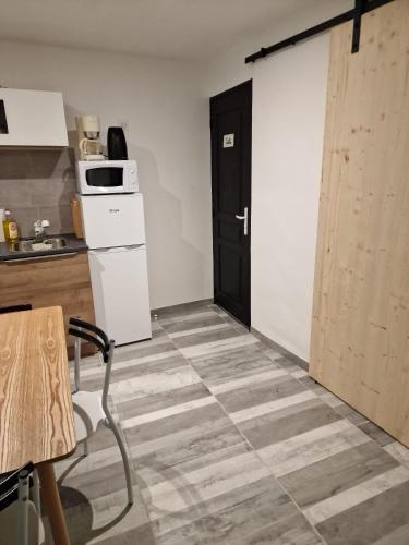 a room with a kitchen with a door and a table at Comme à la maison in Gannat