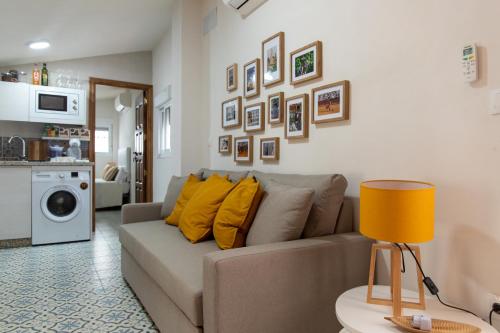 een woonkamer met een bank met gele kussens bij Apartamentos San Francisco in Sevilla