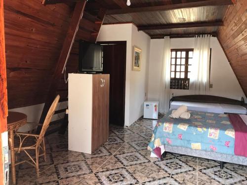 a bedroom with a bed and a television in a room at Estância das Nascentes in Salesópolis
