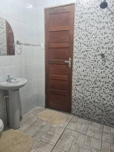 a bathroom with a sink and a wooden door at casa de praia in Macapá