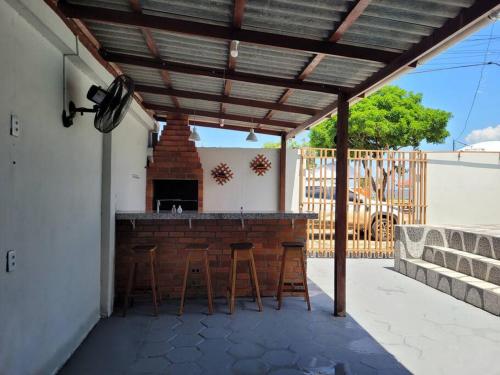 um pátio com um bar com bancos sob uma pérgula em casa de praia em Macapá