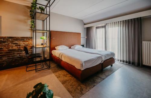 a hotel room with a bed and a table and a chair at Hotel De Zeeuwse Stromen in Renesse