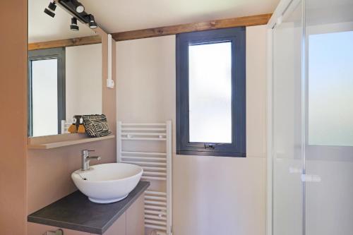 baño con lavabo blanco y ventana en Camping les vergers de Squividan ***, en Tréffiagat