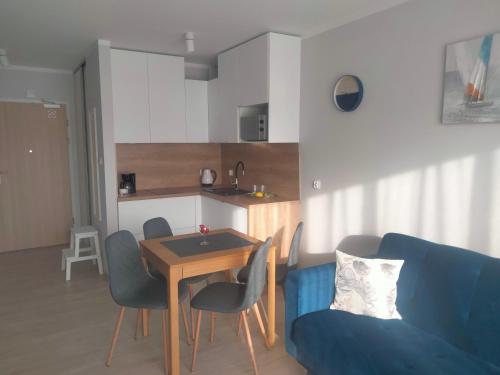 a living room with a blue couch and a table at Apartament Nawigator Rybacka 12 b in Kołobrzeg