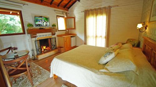 um quarto com uma cama e uma lareira em Pousada Charme da Montanha em Monte Verde