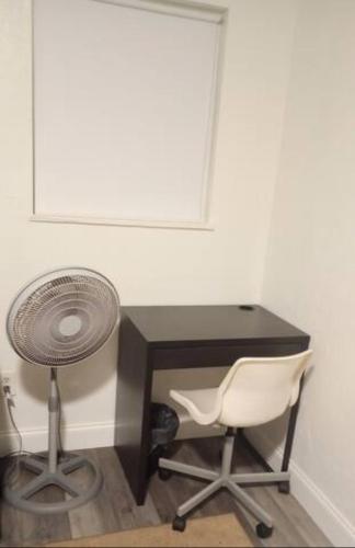 a desk with a fan and a chair in a room at Lenny's Cooperative Hostel in Clearwater