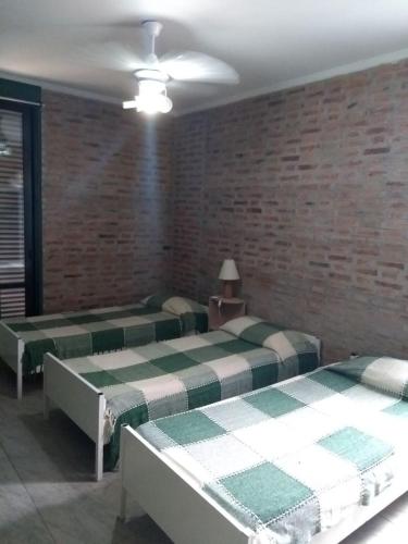 dwa łóżka w pokoju z ceglaną ścianą w obiekcie Concordia Casa barrio residencial w mieście Concordia