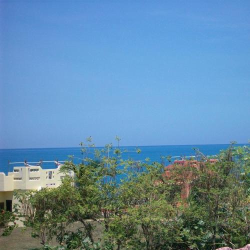 a white building with the ocean in the background at Brytan Villa in Treasure Beach