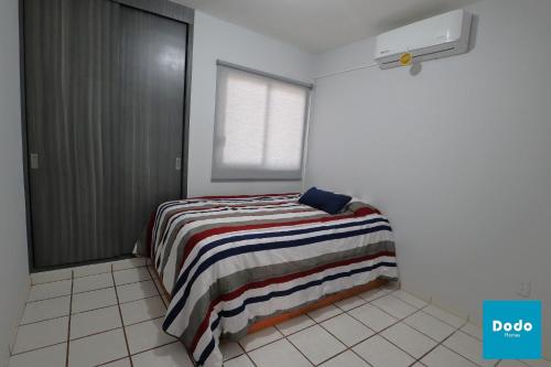 1 dormitorio con 1 cama con manta a rayas en Condominios Plaza San Ignacio, en Mazatlán