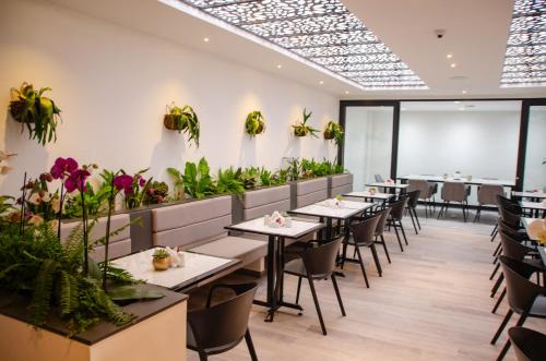 un restaurante con mesas, sillas y plantas en Hotel ByHours Las Américas en Bogotá