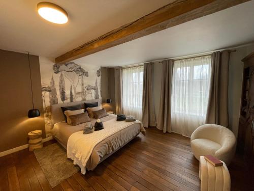 a bedroom with a large bed and a chair at Maison Longue de La Cassine in Vendresse