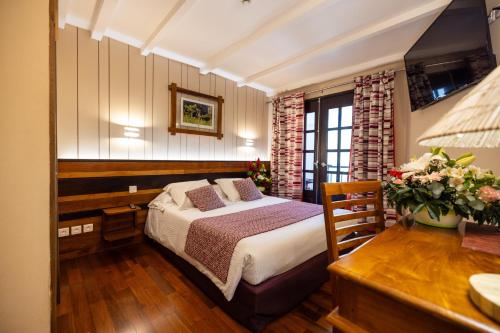 a bedroom with a bed and a table and a desk at Le Vieux Cep in Cilaos