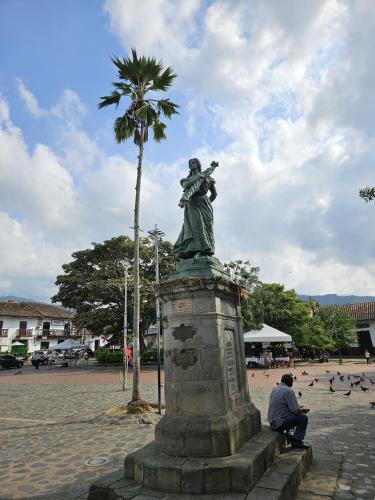 a man sitting next to a statue of a woman at Celestino - Casa de Huespedes in Guaduas