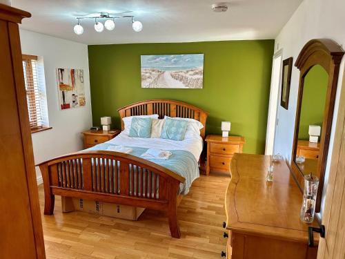 a bedroom with a bed with a green wall at Yr Encil in Gaerwen