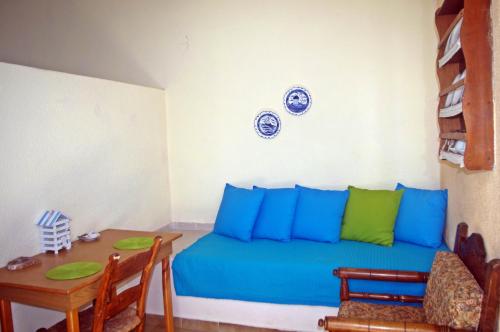 Habitación con cama azul, mesa y platos en la pared. en Rania Studios, en Poros