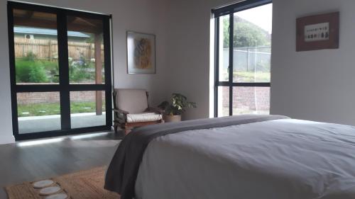 a bedroom with a bed and a large window at Blombos Self-Catering House in Franskraalstrand
