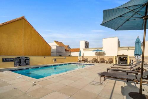 a swimming pool with an umbrella and chairs and a table at Stylish in Sunny Santa Monica walk to Beach & Pier in Los Angeles